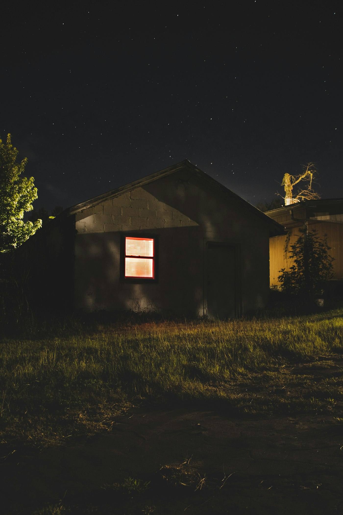 Maison isolée dans la nuit, une seule fenêtre éclairée